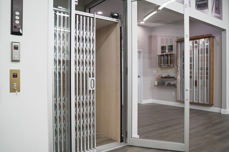Elevator Showroom showing partially open scissor style gate in clear/silver aluminum and 200 Cab in unfinished maple