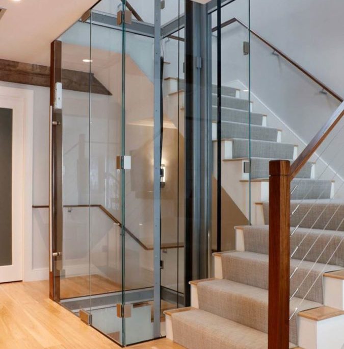 Showing all glass hoistway built around stairs with main guide rail on right
